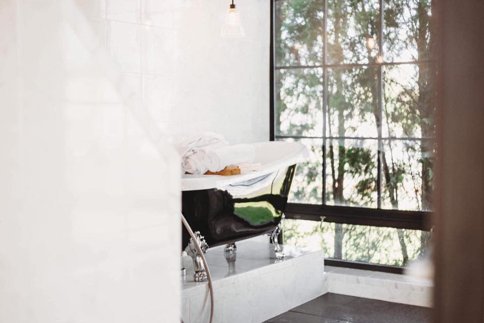 Clawfoot bathtub beside a tall window in the salon's bathing area