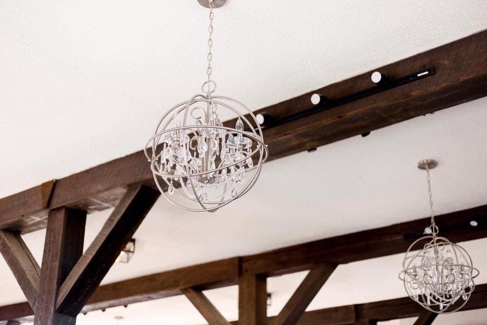 Crystal orb chandeliers hanging from dark wood ceiling beams