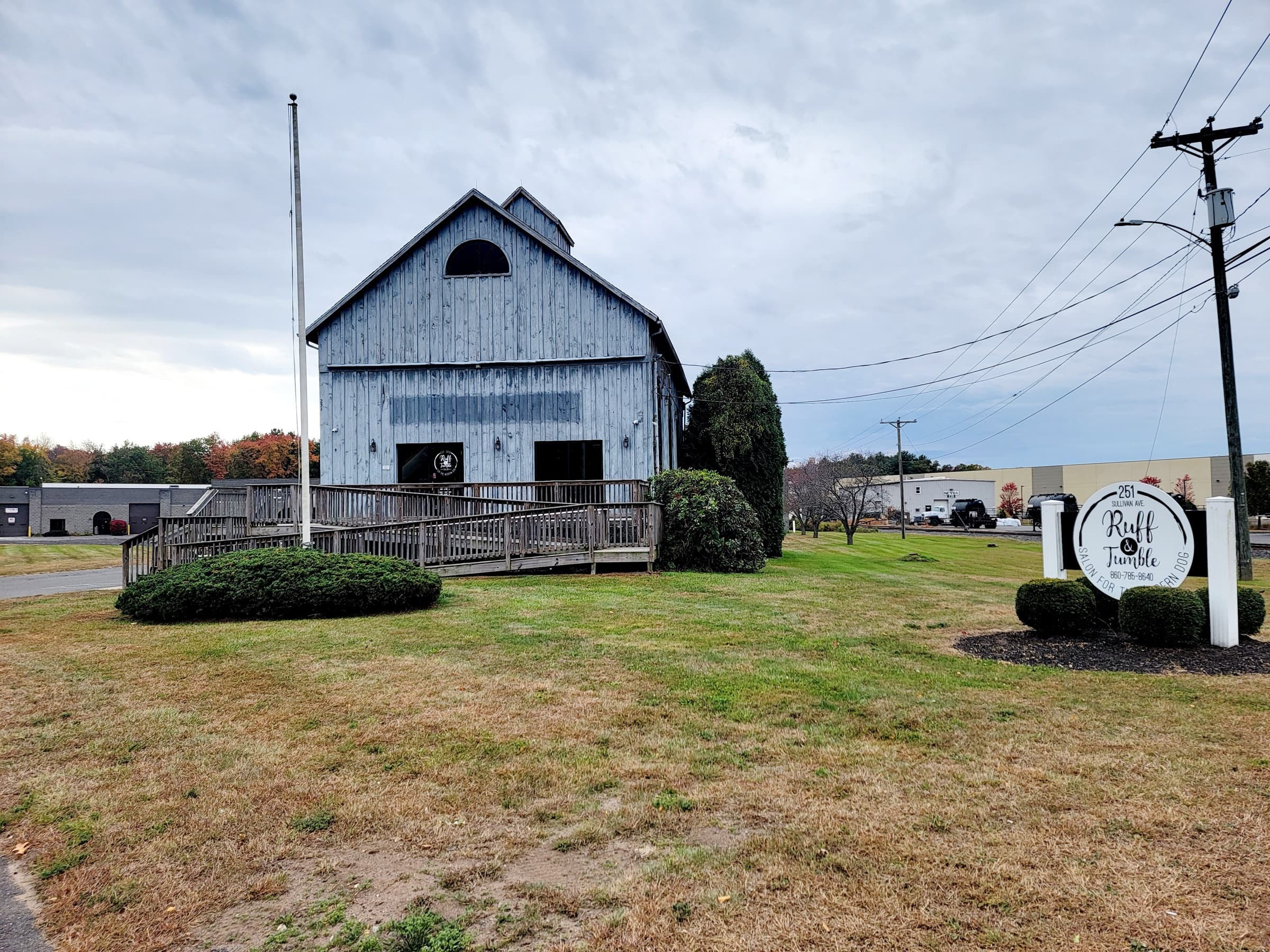 Ruff & Tumble’s South Windsor salon, a gray wooden barn with the salon’s round sign out front